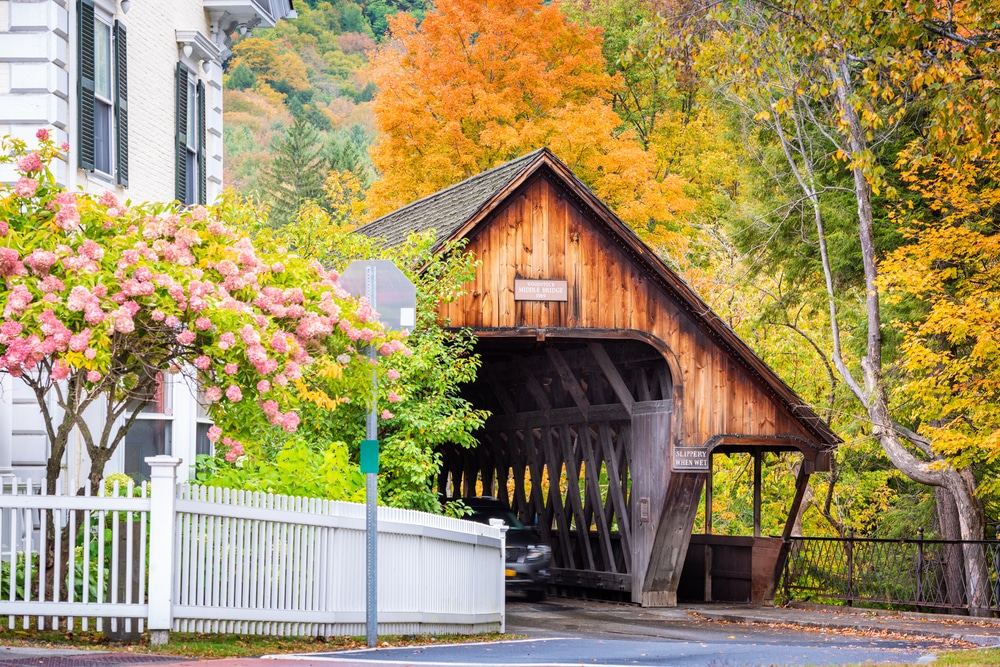The scenic bridge in Woodstock, VT surrounded by Vermont fall foliage